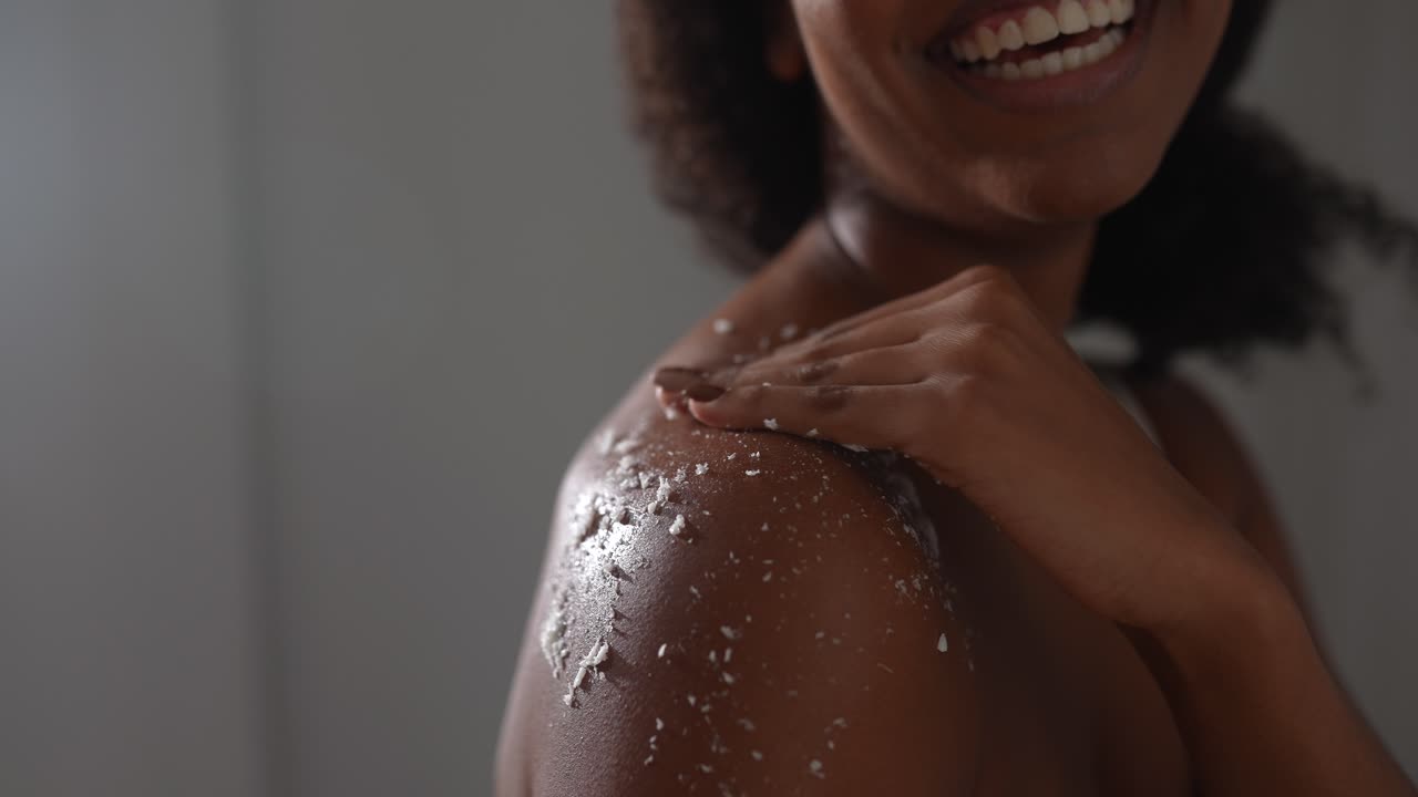 mujer aplicando exfoliante corporal en el hombro