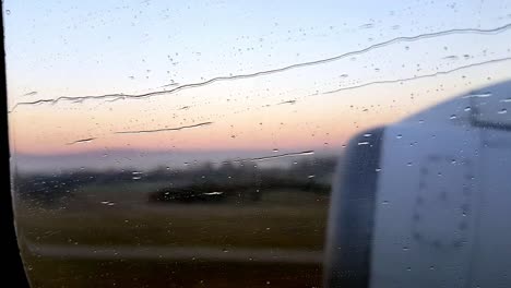 Wassertropfen,-Die-Auf-Einem-Fenster-Fließen,-Blick-Auf-Den-Reaktor-Und-Die-Berge-Während-Des-Starts-Bei-Sonnenaufgang