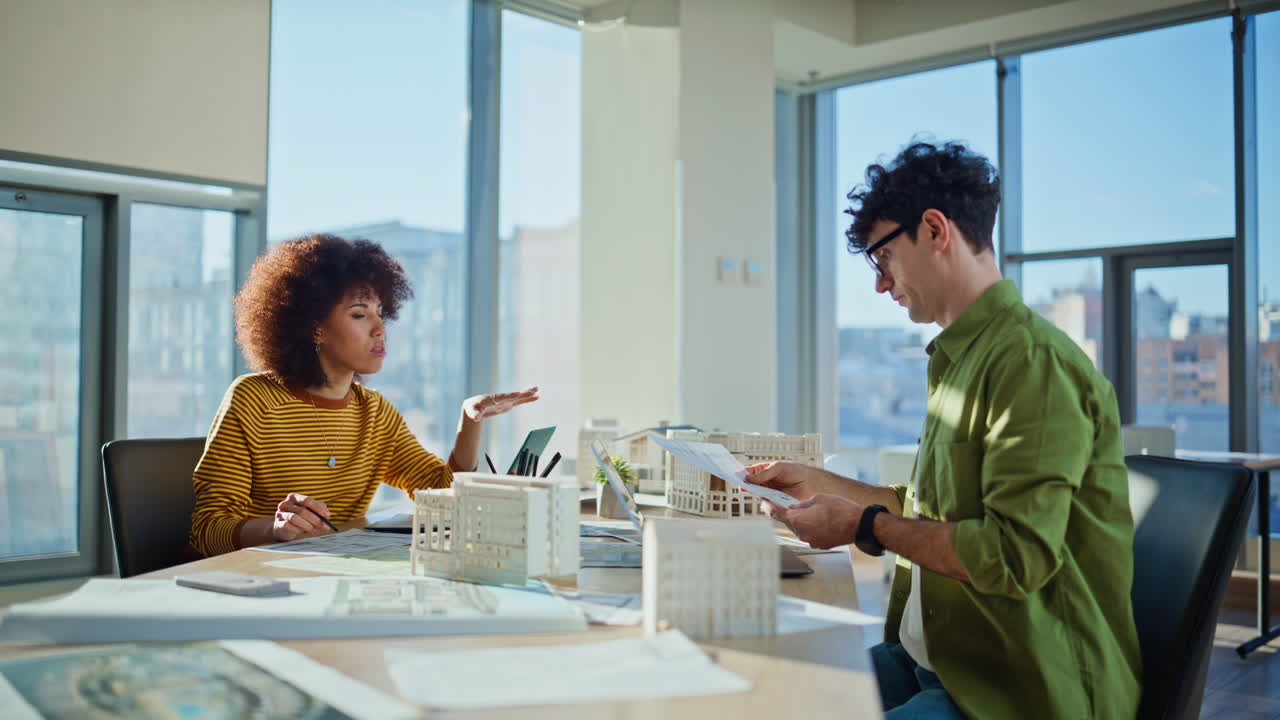 Two architects working laptops developing uban construction plan in office space