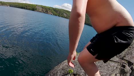 jump off tall cliff with young white male into blue lake, pov slow motion wide action tracking