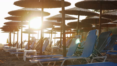 Empty-chaise-longues-on-resort-and-people-leaving-beach-at-sunset