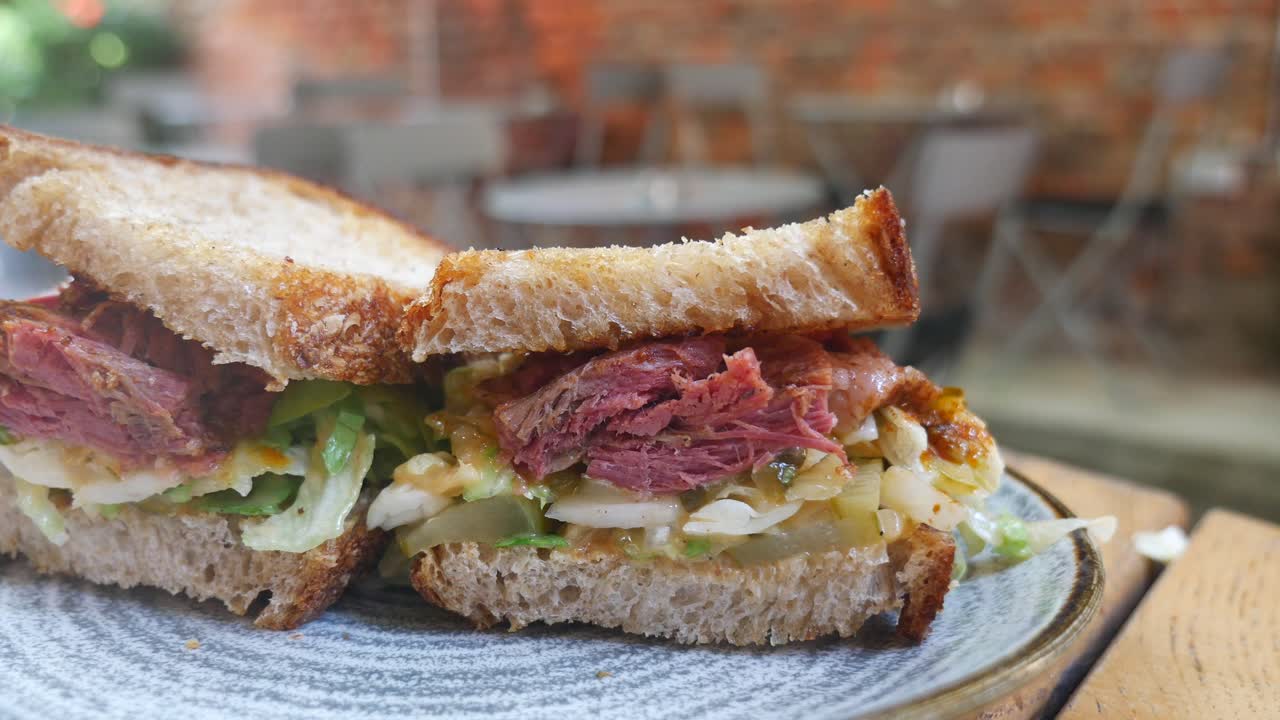 Close-up of a deli sandwich with sliced meat, lettuce, and pickles