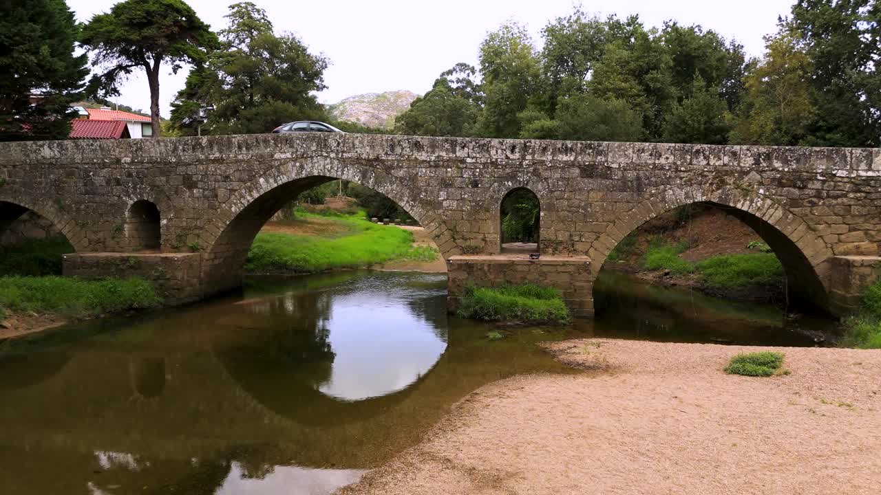 Historic Romanesque bridge over tranquil river, capturing peaceful nature scene