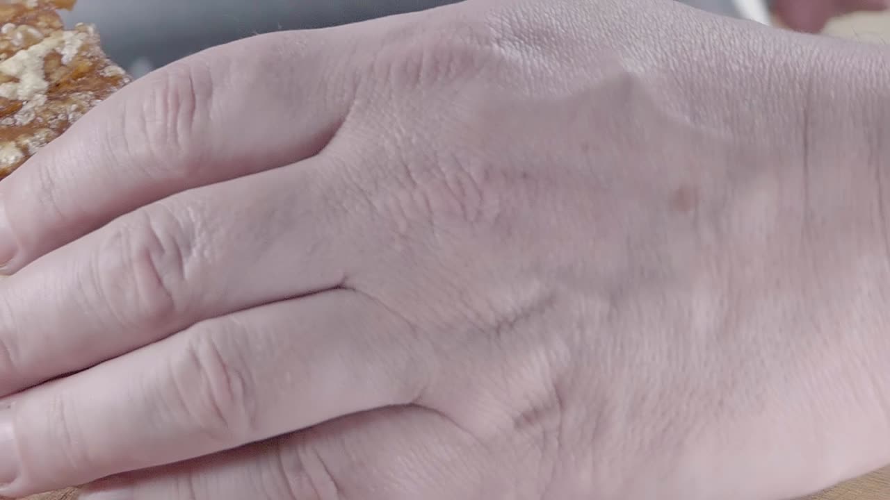 toma en cámara lenta de cortar crujientes chicharrones de cerdo en una tabla de cortar de madera