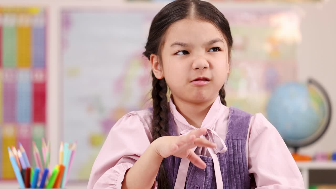 Elementary school girl grimaces and waves hand, reacting to bad odor in bright classroom