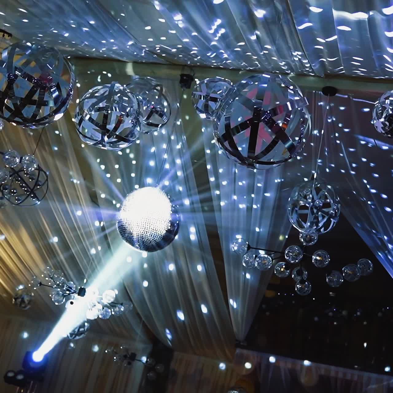 Silver light from shining balls. Disco ball glittering from the ceiling at night club. Celebration concept.