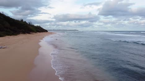 Ocean-background,-bright-blue-sky-with-white-clouds,-golden-sand-beach-and-waves-at-open-sea-approaching-horizon