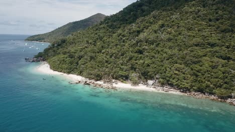 Drone-aerial-that-pans-the-edge-of-a-tropical-island-with-clear-blue-water-and-sandy-beaches