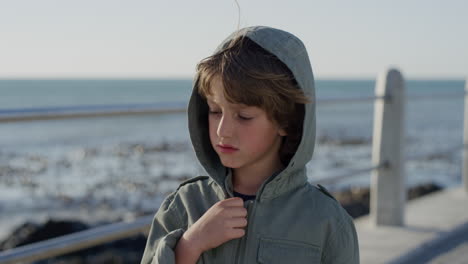 portrait calm little caucasian boy enjoying ocean seaside wearing jacket on windy sunny day slow motion