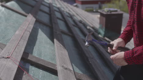 trabajador de la construcción calificado con casco amarillo trabajo sin guantes martillar cuidadosamente colocar tejas de techo seguras casa en construcción columpiarse de manera experta coloca las tejas asegurando un techo sólido y confiable