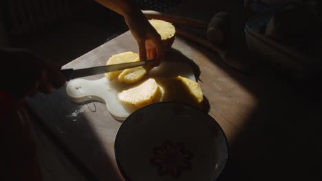 hands slicing pineapple, and putting them into a bowl