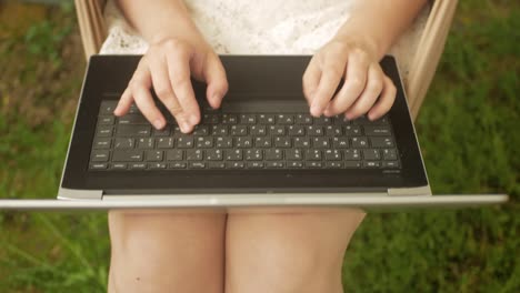 mujer monta en un columpio y se comunica con amigos usando una computadora portátil. pantalla verde, descanso en el patio de la casa. al aire libre. redes sociales, internet, mensajes. en la naturaleza.