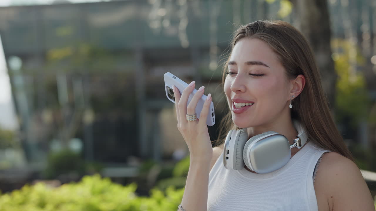 Woman with headphones using phone in urban environment