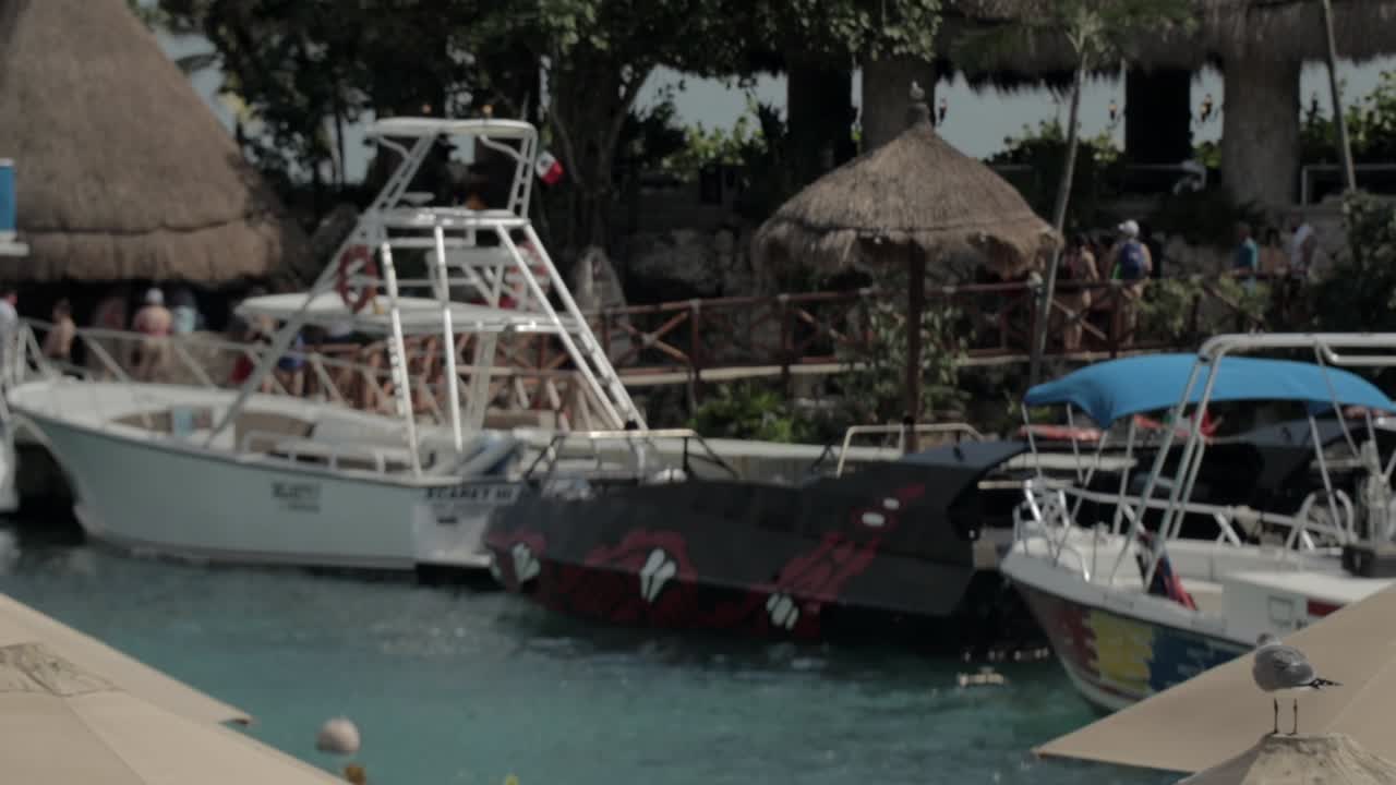Beach Chairs and Umbrellas on Beach with Speed Boats in the Background at Xcaret Park Mexico