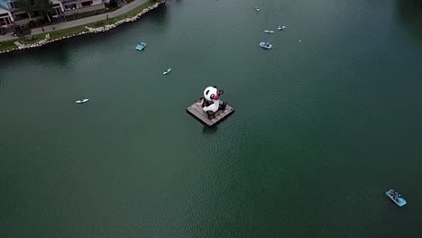 kayakistas alrededor de la enorme figura del panda en medio del tranquilo lago en washington, estados unidos - toma aérea
