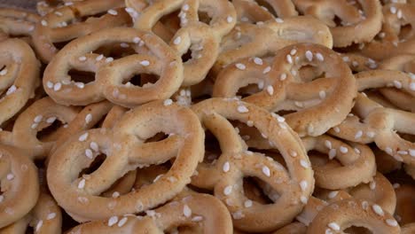 pile of pretzels sprincled with sesame rotate on a turntable. unhealthy but delicious fast food.