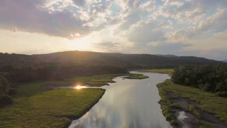 Filmische-Drohnenansicht,-Während-Sie-Bei-Sonnenuntergang-über-Den-Fluss-Fliegt