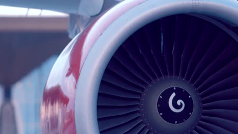 the plane is standing next to the airport building, the red turbine rotates