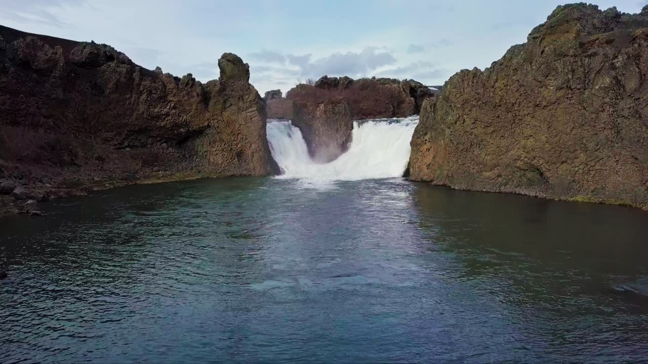 cascadas gemelas que desembocan en un estanque en islandia rodeadas de terreno rocoso