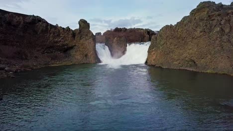 twin waterfalls gushing into pond in iceland surrounded by rocky terrain