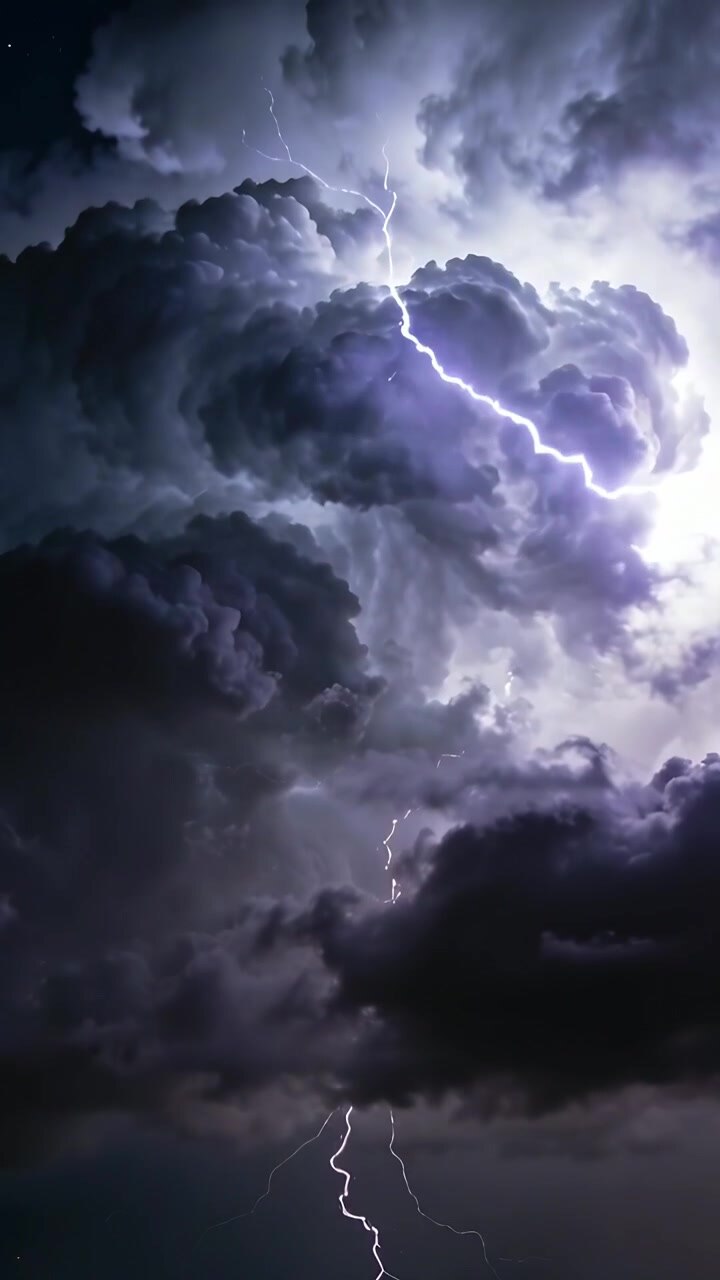 Video verticale: Nuvola temporalesca con fulmini che illuminano gli strati interni di notte con scariche ramificate.