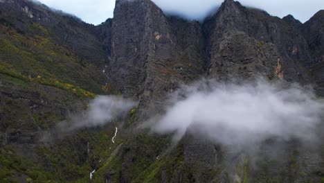 Clouds-and-rocky-mountains-in-Autumn-with-high-peaks-covered-by-fog-and-creeks-flowing