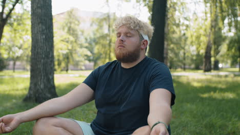 obese man practicing yoga meditation in park