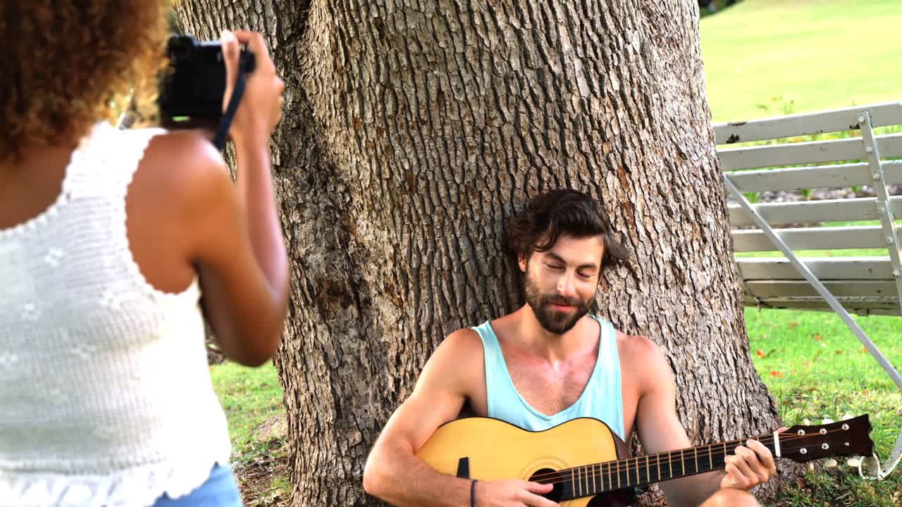 mujer tomando una foto de un hombre tocando la guitarra