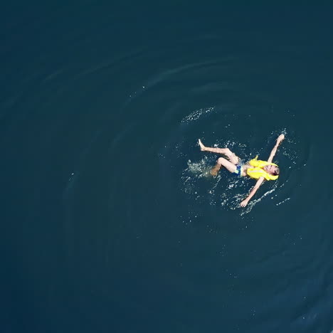 little boy swimming in crystal clear water. happy children on summer vacation. aerial view.