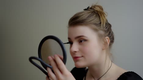 Close-up-of-girl-in-front-of-mirror-applying-mascara