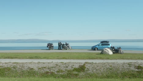 motociclistas descansando cerca de la carretera en un fiordo impresionante en el norte de noruega, turistas motociclistas disfrutando de la hermosa vista en el norte de noruega en un día soleado