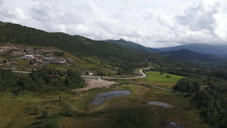 Die-Drohne-Bewegt-Sich-Horizontal-Und-Erfasst-Das-Tal-Von-Rauland,-Telemark,-Norwegen-Und-Eine-Kleine-Siedlung-An-Der-Seite