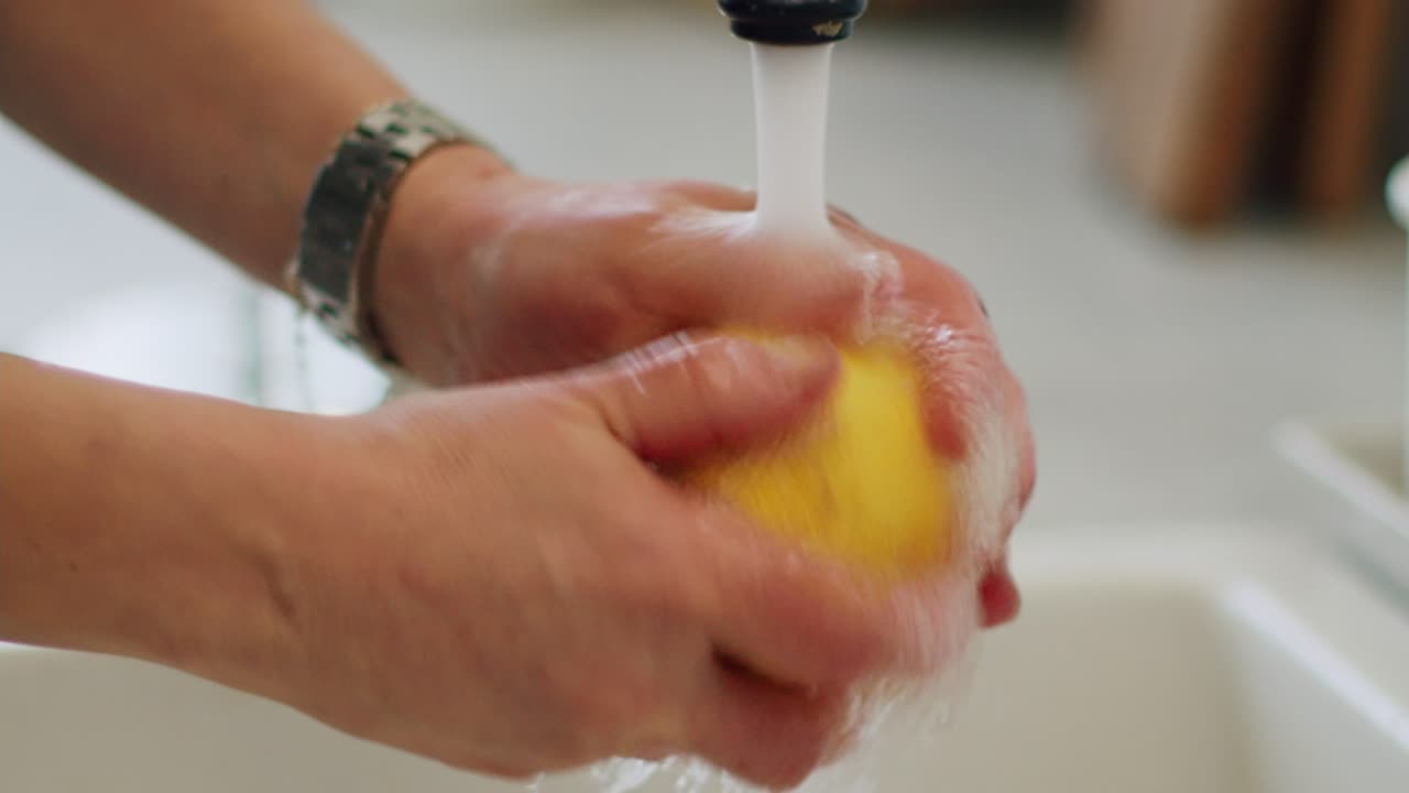 Mujer lavando limón bajo el grifo en el fregadero.