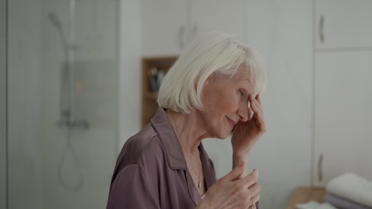 Senior woman in bathroom applying skincare