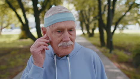 portrait of athletic senior sport runner man wearing earphones listening music, smiling, cardio