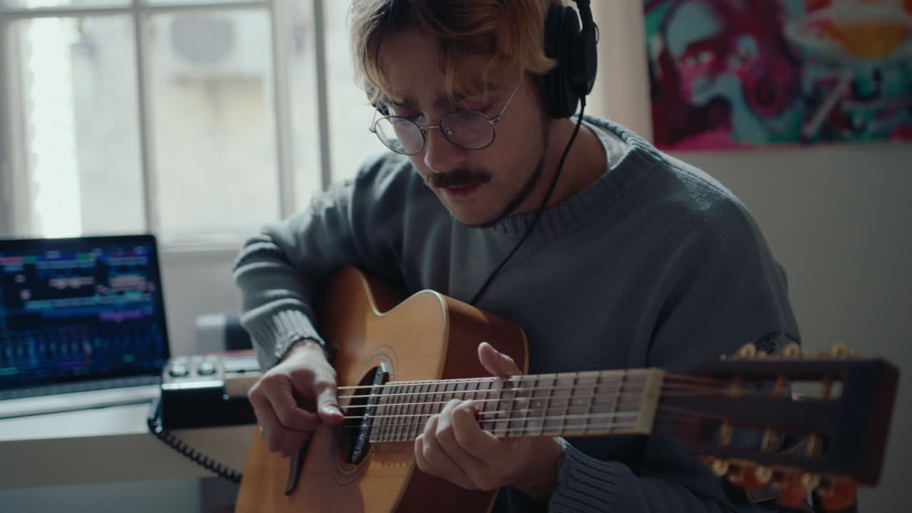 Young Musician in Headphones Playing the Guitar at Home