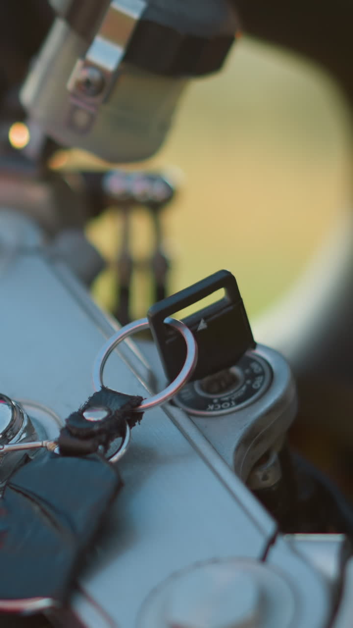 A close-up of a person's hand inserting a key into the ignition of a motorcycle