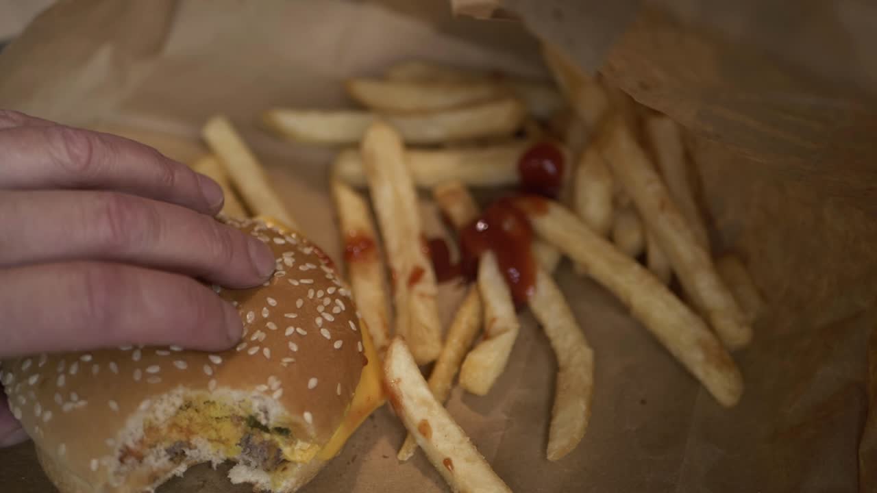 mano recogiendo hamburguesa con queso con papas fritas tiro medio