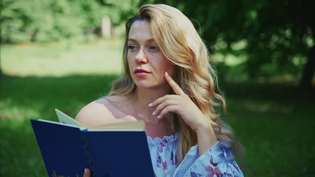 Giovane donna che legge un libro in un parco verde