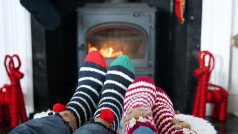 close up de una pareja de mayores con calcetines de navidad calentando los pies en la estufa de leña