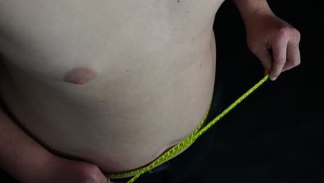 young man measuring his belly with meter close up