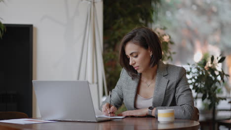 Mujer-De-Negocios-Escribiendo-Algo-En-El-Cuaderno.-Mujer-Emprendedora-Estudiante-Que-Estudia-Escribir-Notas-En-El-Lugar-De-Trabajo-Cerca-De-La-Computadora.-La-Mano-De-Una-Mujer-Escribiendo-En-Un-Cuaderno-Blanco-Sobre-La-Mesa.