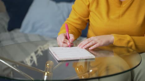 woman is writing something on sheets of paper at glass table with pen. she reads something and corrects it with pen. studying something, preparing for speech, checking contract, training, lecture