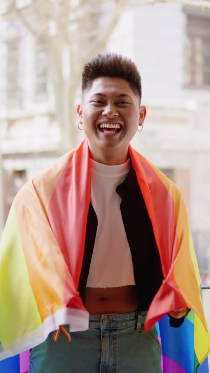 Person wrapped in a rainbow flag smiling