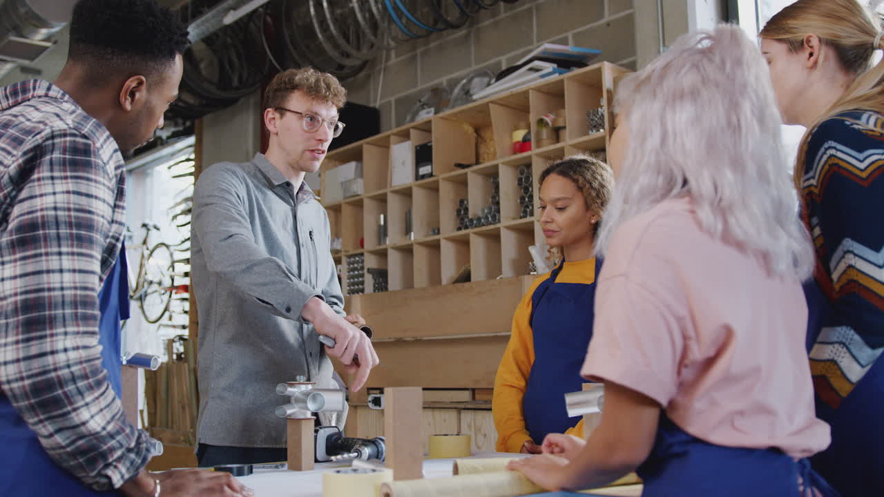 equipo multicultural de aprendices en el taller aprenden a ensamblar un marco de bicicleta construido a mano juntos