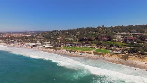 people swimming and surfing at del mar beach with powerhouse park in san diego, california, usa