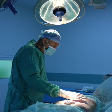 doctor doing liposuction procedure. surgeon performing cosmetic surgery on patient's belly in hospital. blue light in the operating room