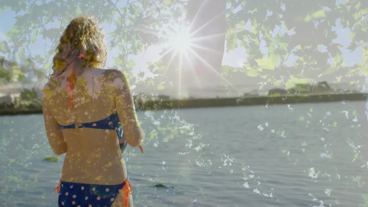 Donna in costume da bagno blu che afferra un asciugamano e lo srotola vicino al lago per avvolgersi la vita dopo il bagno.