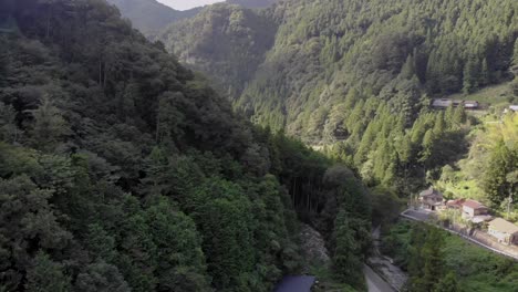 Schwenk-Drohnenaufnahme-Der-Berge-Auf-Dem-Land-In-Japan-Mit-Grünen-Bäumen-Und-Häusern