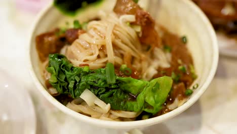 chopsticks lifting noodles from a savory dish